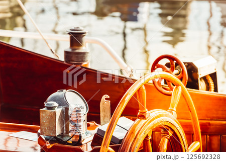 Wooden boat steering wheel and ship details creating nautical atmosphere Wooden boat steering wheel and ship details creating nautical atmosphere 125692328