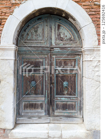 Old arched wooden door with lion knockers 125692416