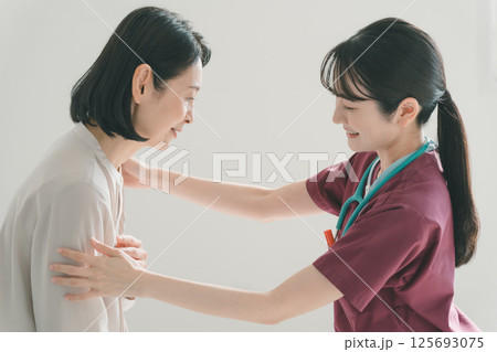 50代女性の胸の痛みを診察する女性医師 125693075