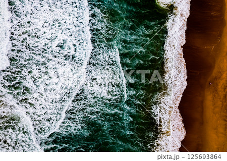 Top view Dark waves crashing on sandy shore beach background,Amazing waves sea nature background Top view Dark waves crashing on sandy shore beach background,Amazing waves sea nature background 125693864