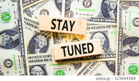 Stay tuned symbol. Concept words Stay tuned on wooden blocks on a beautiful background from dollar bills. Dollar bills. Business, support, motivation, psychological and stay tuned concept. Copy space. 125694369