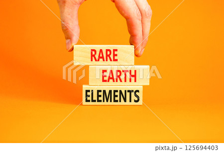 Rare earth elements symbol. Concept words Rare earth elements on beautiful wooden block. Businessman's hand. Beautiful orange background. Business and rare earth elements concept. Copy space. 125694403