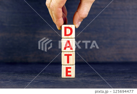 Date symbol. Concept word Date on beautiful wooden blocks. Businessman hand. Beautiful black table black background. Business and date concept. Copy space. Date symbol. Concept word Date on beautiful wooden blocks. Businessman hand. Beautiful black table black background. Business and date concept. Copy space. 125694477