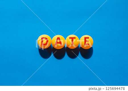 Date symbol. Concept word Date on beautiful yellow ping pong balls. Beautiful blue table blue background. Business and date concept. Copy space. Date symbol. Concept word Date on beautiful yellow ping pong balls. Beautiful blue table blue background. Business and date concept. Copy space. 125694478