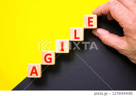 Agile symbol. Concept word Agile on beautiful wooden blocks. Beautiful yellow and black background. Businessman hand. Business agile concept. Copy space. 125694490