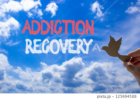 Addiction recovery symbol. Concept words Addiction recovery on beautiful blue sky. Psychologist hand, wooden bird. Beautiful blue sky cloud background. Psychology addiction recovery concept Copy space Addiction recovery symbol. Concept words Addiction recovery on beautiful blue sky. Psychologist hand, wooden bird. Beautiful blue sky cloud background. Psychology addiction recovery concept Copy space 125694588