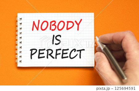 Nobody is perfect symbol. Concept words Nobody is perfect on beautiful white note. Beautiful orange background. Businessman hand. Business motivational lifestyle nobody is perfect concept. Copy space. Nobody is perfect symbol. Concept words Nobody is perfect on beautiful white note. Beautiful orange background. Businessman hand. Business motivational lifestyle nobody is perfect concept. Copy space. 125694591