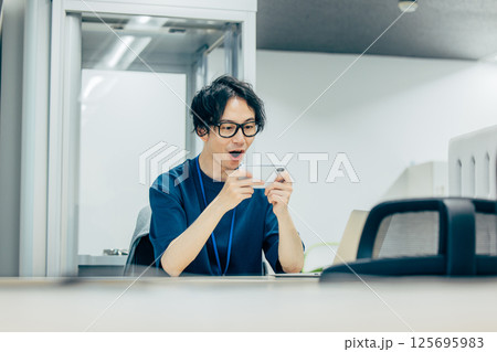 職場でスマホゲームをする男性 125695983