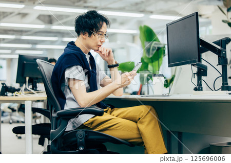 オフィスでスマホを操作する男性 オフィスでスマホを操作する男性 125696006