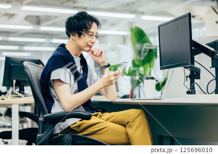 オフィスでスマホを操作する男性 125696010
