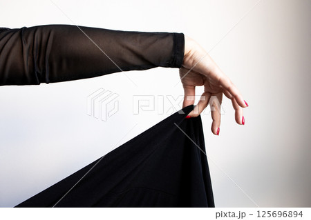 Female hand draping black fabric with red nails and sheer sleeve Female hand draping black fabric with red nails and sheer sleeve 125696894