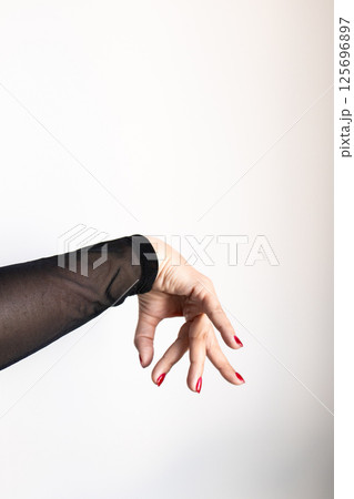 Female hand with red nails in black sheer sleeve on white background 125696897
