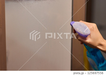 Cleaning a glass surface effectively with a spray bottle to achieve a clear, shiny finish Cleaning a glass surface effectively with a spray bottle to achieve a clear, shiny finish 125697556