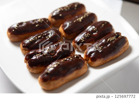 Eight classic eclairs arranged neatly on a white plate. Eight classic eclairs arranged neatly on a white plate. 125697772