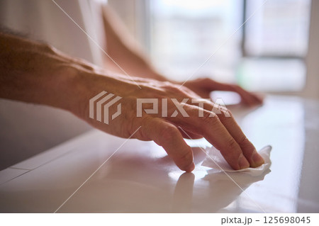 A person is meticulously hand cleaning a surface using a cloth in a bright and inviting environment 125698045
