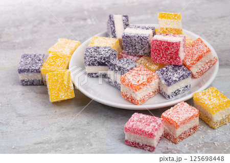 Cubes of multi-colored marmalade in powdered sugar on plate. The concept of baby sweets. 125698448
