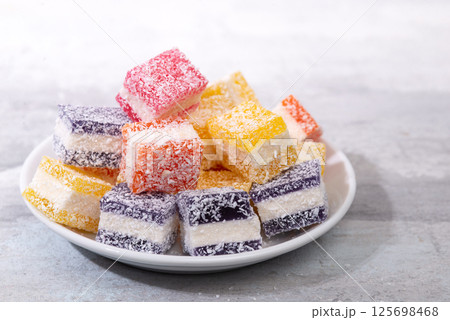 Cubes of multi-colored marmalade in powdered sugar on plate. The concept of baby sweets. 125698468