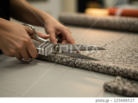Seamstress cutting fabric with scissors on pattern in atelier 125698517
