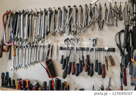 Wall-mounted tool set with wrenches, pliers, screwdrivers and hand tools in workshop Wall-mounted tool set with wrenches, pliers, screwdrivers and hand tools in workshop 125699287