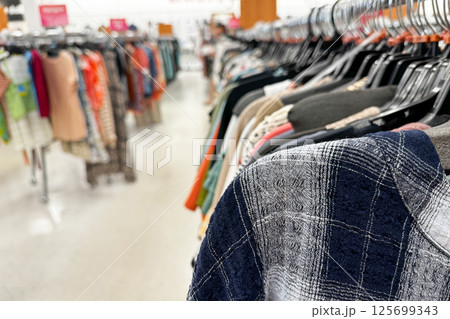 A close-up view of clothing racks in a brightly lit retail store featuring various garments on hangers 125699343
