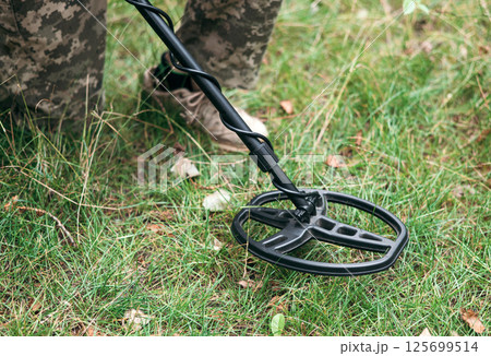 Soldier using a metal detector in fields. Ukrainian Explosive Ordnance Disposal Officer detecting metal by metal detector device Soldier using a metal detector in fields. Ukrainian Explosive Ordnance Disposal Officer detecting metal by metal detector device 125699514