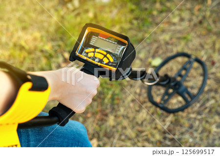 A man's hand with a metal search device. Treasure hunters. A metal detector in a person's hand. Search for jewelry. 125699517