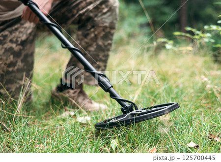 A military sapper with a metal detector in the field. A Ukrainian explosive technician carries out demining work. 125700445