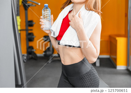 Good shape, strong and fit women in sportswear sitting and drinking water after workout at home. Good shape, strong and fit women in sportswear sitting and drinking water after workout at home. 125700651