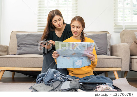 Exciting travel planning: Friends analyzing maps and packing 125700797