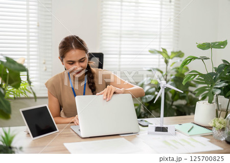 ESG Sustainability focus with woman working on laptop in green office 125700825