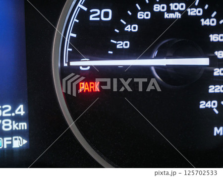 Close up of a car's dashboard displaying an illuminated parking brake warning light, indicating that the parking brake is engaged Close up of a car's dashboard displaying an illuminated parking brake warning light, indicating that the parking brake is engaged 125702533