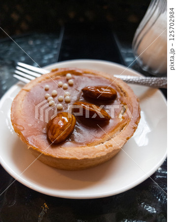 Sweet delicacy adorned with almonds served on a white plate 125702984