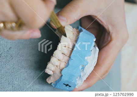 Crafting intricate ceramic dentures with precision in a dental workshop 125702990
