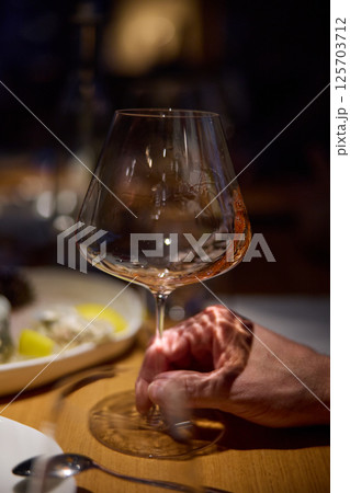 Champagne tasting, Wine glasses are on the table, stylish table setting, A man's hand holds a beautiful elegant glass with rose sparkling wine, an intimate light, a plate with oysters and lemon Champagne tasting, Wine glasses are on the table, stylish table setting, A man's hand holds a beautiful elegant glass with rose sparkling wine, an intimate light, a plate with oysters and lemon 125703712