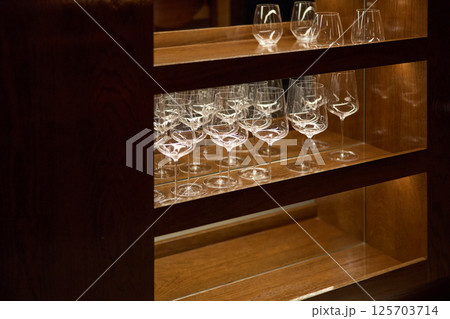 Clean wine glasses are in the wine cabinet in restaurant, local illumination Clean wine glasses are in the wine cabinet in restaurant, local illumination 125703714