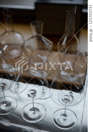 Clean wine glasses are on the table of a special wine cabinet, stylish table setting, ice, bottle of sparkling wine, light from window, decanter and degasser 125703731