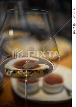 A glass of sparkling wine in close-up, Champagne tasting, Wine glasses are on the table, stylish table setting, sparkling wine bubbles, oysters and sea urchins, special sauce 125703735