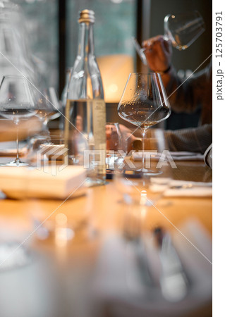 Champagne tasting, Wine glasses are on the table, stylish table setting, A man's hand holds a beautiful elegant glass with rose sparkling wine, an intimate light, a plate with oysters and lemon 125703791