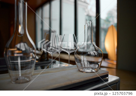 Clean wine glasses are on the table of a special wine cabinet, stylish table setting, ice, bottle of sparkling wine, light from window, decanter and degasser Clean wine glasses are on the table of a special wine cabinet, stylish table setting, ice, bottle of sparkling wine, light from window, decanter and degasser 125703796