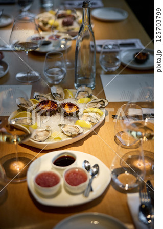 Champagne tasting, Wine glasses are on the table, stylish table setting, sparkling wine bubbles, oysters and sea urchins, special sauce Champagne tasting, Wine glasses are on the table, stylish table setting, sparkling wine bubbles, oysters and sea urchins, special sauce 125703799