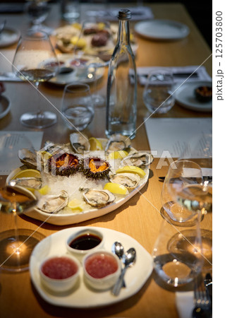 Champagne tasting, Wine glasses are on the table, stylish table setting, sparkling wine bubbles, oysters and sea urchins, special sauce Champagne tasting, Wine glasses are on the table, stylish table setting, sparkling wine bubbles, oysters and sea urchins, special sauce 125703800