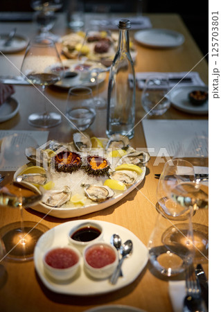 Champagne tasting, Wine glasses are on the table, stylish table setting, sparkling wine bubbles, oysters and sea urchins, special sauce 125703801