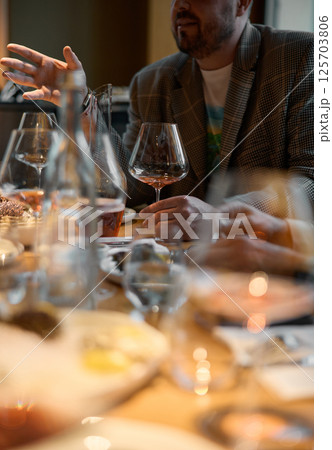 Champagne tasting, Wine glasses are on the table, stylish table setting, wine is poured from a bottle and decanter, sparkling wine bubbles, snacks, people smell the aroma and taste the wine 125703806