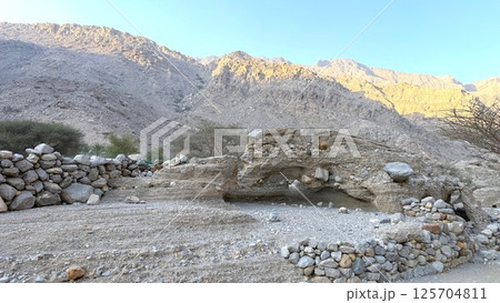 Massive weathered rock face features vertical fractures and blocky plates, indicating signs of desert exfoliation and natural layering, ideal for educational tourism and geology walks. 125704811
