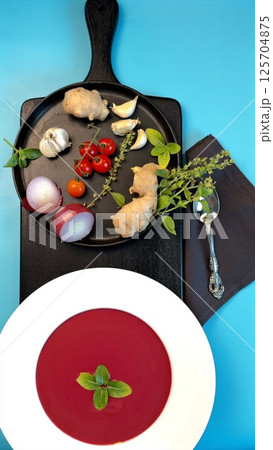 Beetroot soup with smooth texture garnished with fresh herbs, cherry tomatoes, and vibrant greens celebrates clean eating. Natural ingredients highlight unprocessed, wholesome, plant-based dining. 125704875