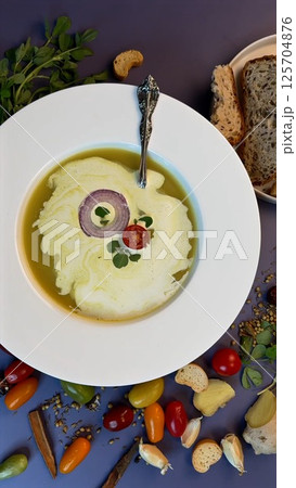 Warm lentil soup with vibrant garnishes and freshly baked bread creates a comforting yet ecological meal. Wholesome flavors align with healthy choice, embracing sustainable, plant-based dining. 125704876