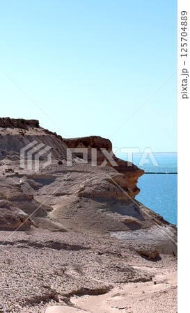 Rocky cliff towering over turquoise waters, revealing dramatic landscape within Ras Mohamed National Park, highlighting rugged coastline and pristine natural environment in Egypt 125704889