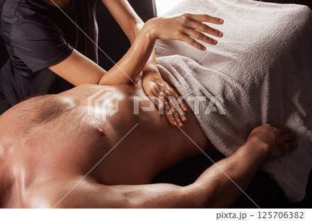 Massage therapist performing deep abdominal and diaphragm massage for muscle release and energy flow. Massage therapist performing deep abdominal and diaphragm massage for muscle release and energy flow. 125706382