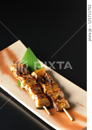 鰻の串焼きを黒背景で撮影 鰻の串焼きを黒背景で撮影 125711702