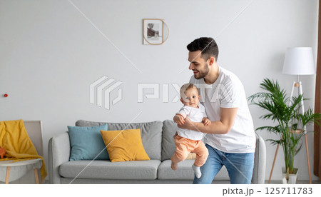 Young dad dancing in the living room with his little child. Generated image 125711783